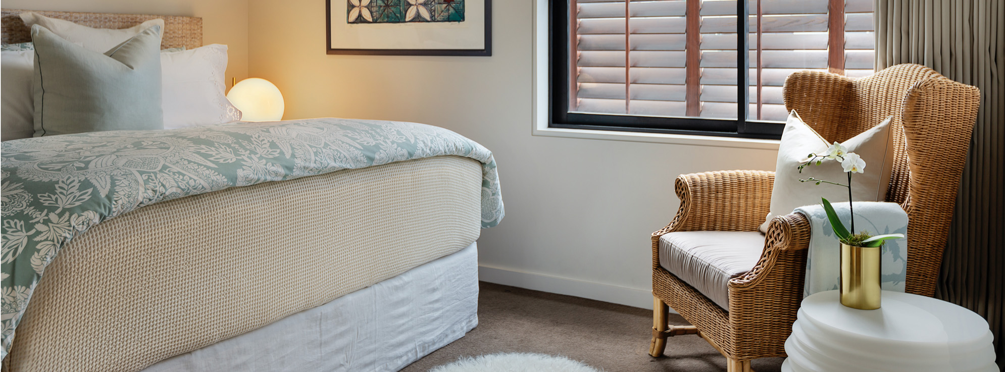 Guest Bedroom with Luxury Linen, Designer Bedside Lamps, Wingback Cane Chair, Phalaenopsis Orchid | Point Residence Auckland